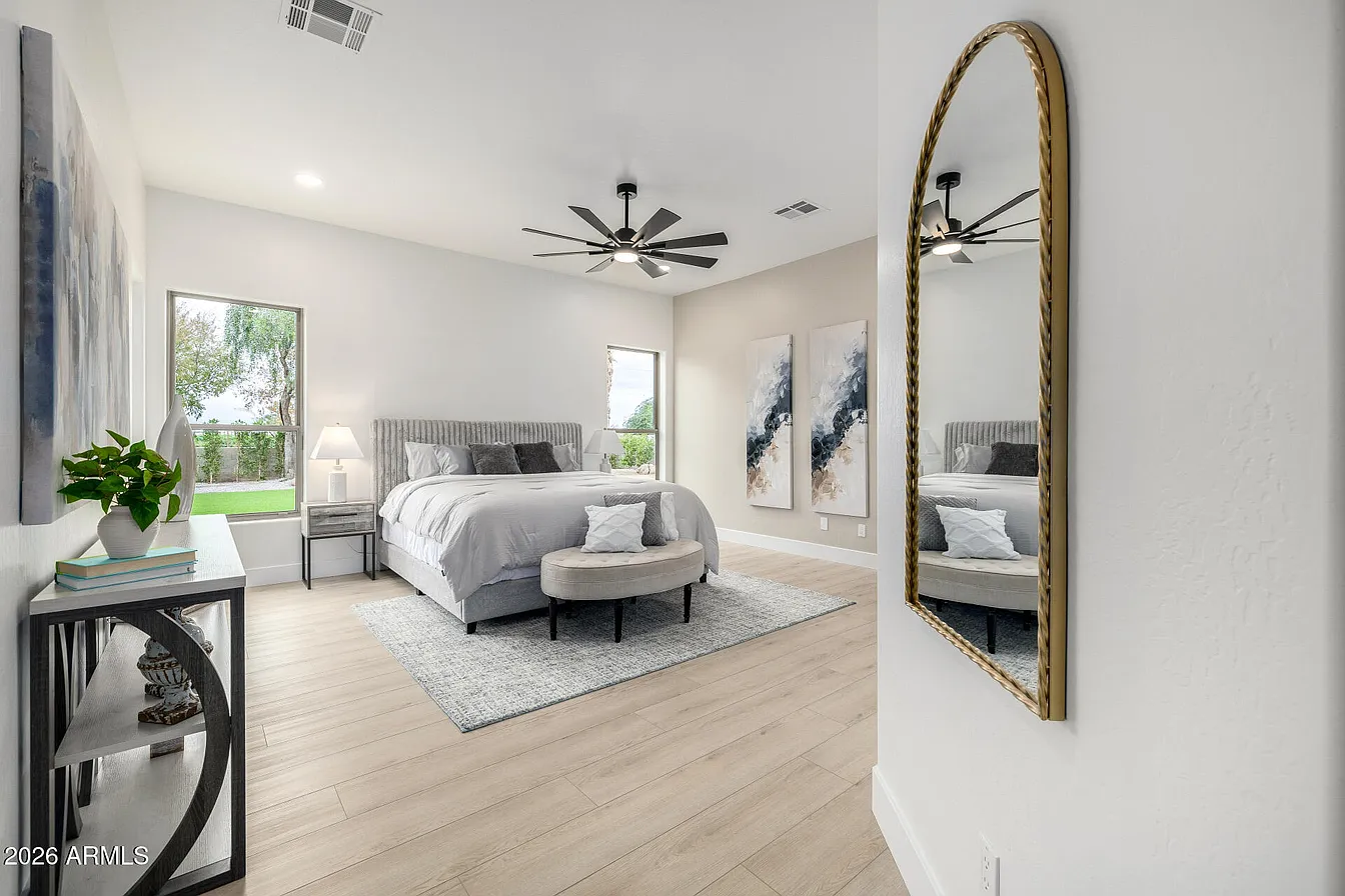 Staged master bedroom with gold arched mirror and modern ceiling fan