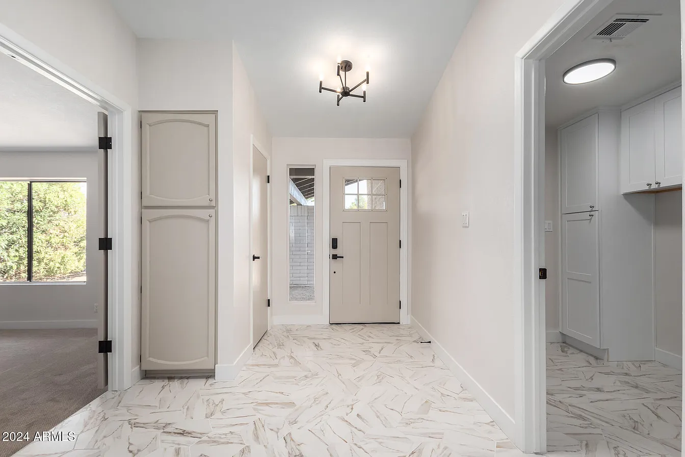 Entryway with marble-look tile flooring and custom built-in storage