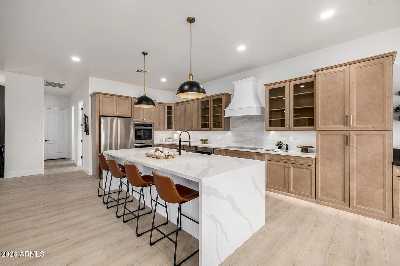 Wood cabinet kitchen with waterfall quartz island and brass pendant lights