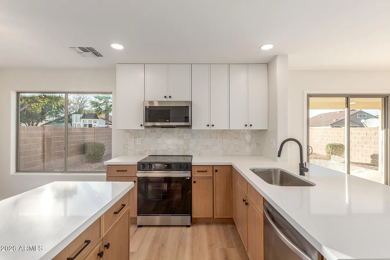 White and wood two-tone kitchen with quartz countertops and tile backsplash