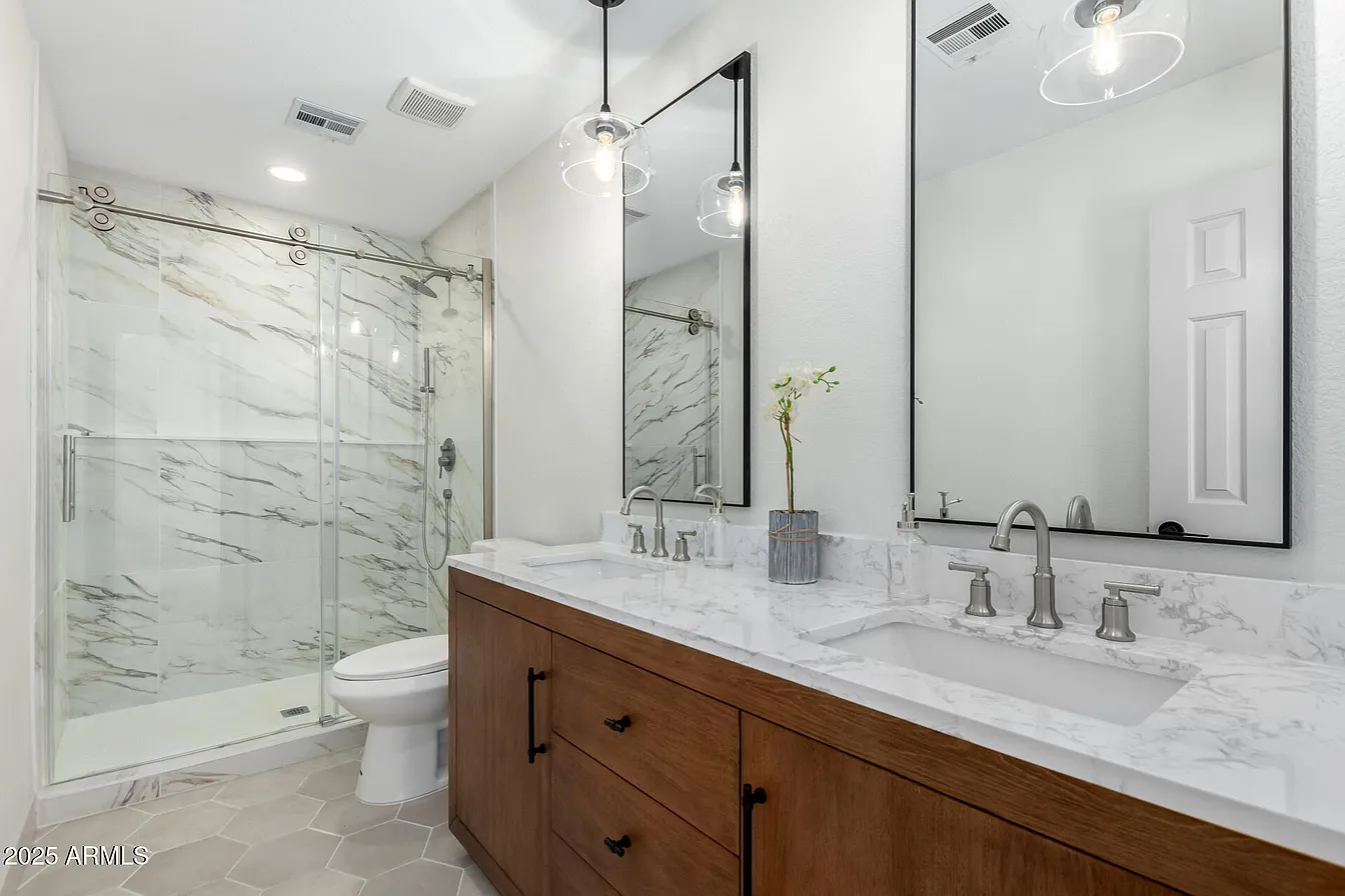 Marble shower with pendant lights and hex tile